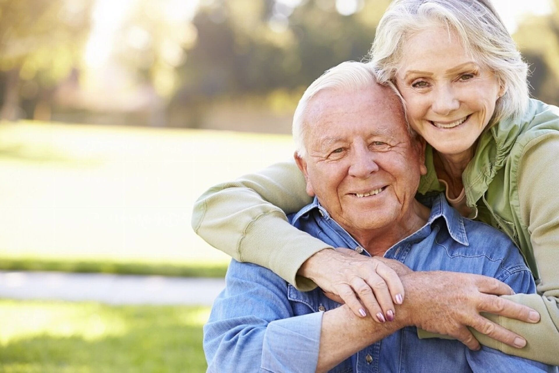 An older couple smiles warmly while embracing outdoors An older couple smiles warmly while embracing outdoors